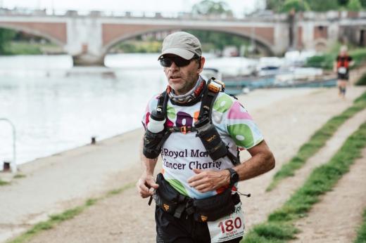 Rob running outside in a colourful Royal Marsden Cancer Charity running vest, cap and sunglasses. 