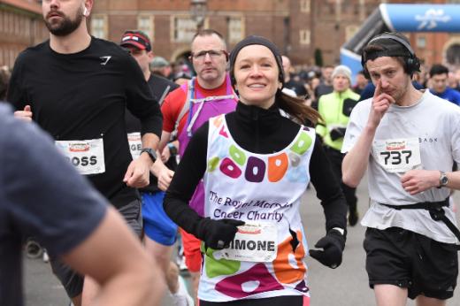 A Team Marsden runner smiles at the camera whilst running the Hampton Court Palace Half Marathon