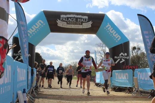 Two runners hold hands as they cross the Palace Half finish line 