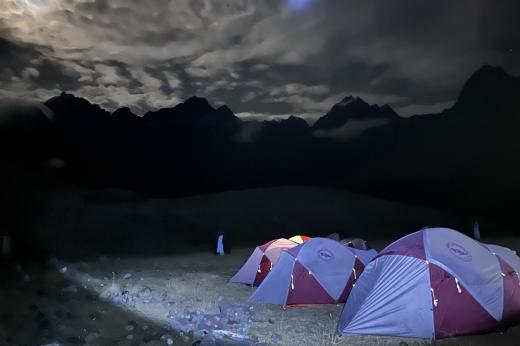 A group of tents in front of mountains at nighttime