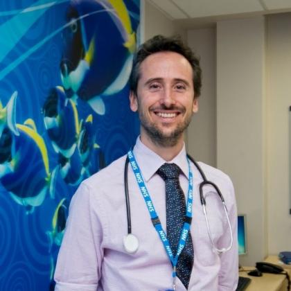 Dr Fernando Carceller, smiling in front of wall with giant photograph of fish