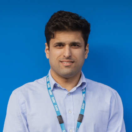 Photo of Dr Masood Moghul against a blue background wearing NHS lanyard