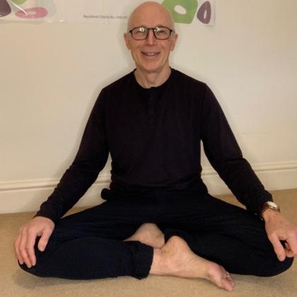 A person sitting in a cross-legged yoga position on the floor 