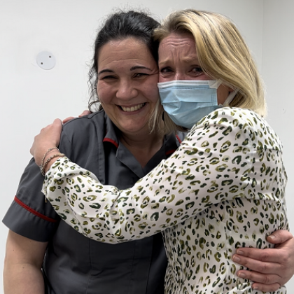A Royal Marsden nurse in uniform smiling and hugging a patient 