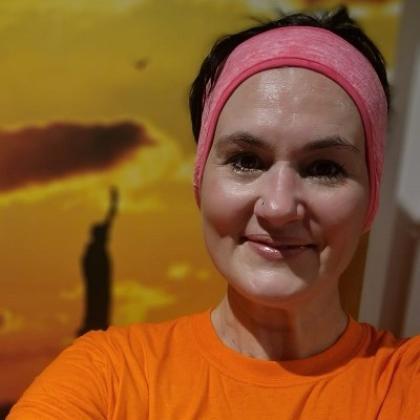 Headshot of a woman in a sweat band and wearing a bright orange Royal Marsden Cancer Charity shirt