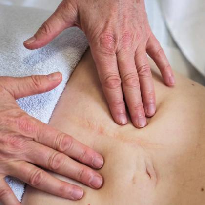 a close up shot of two hands massaging scar tissue on a woman's stomach