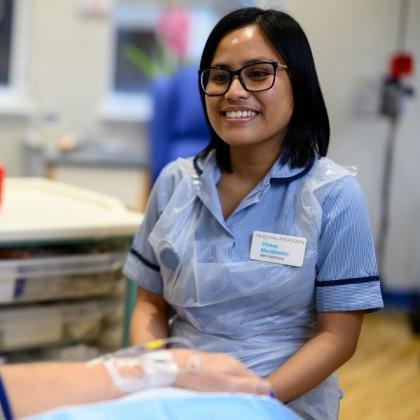 A member of staff at The Royal Marsden smiling at a patient who is receiving treatment in the medical day unit 