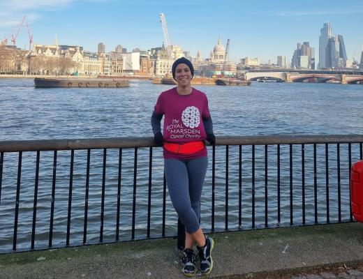 A woman in running gear standing in front of a view across the River Thames and city of London