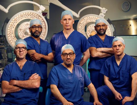 six surgeons in blue scrubs in an operating theatre