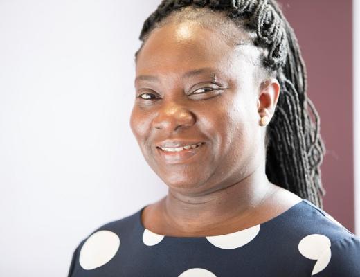 A headshot of The Royal Marsden's Sarah Adomah. She is smiling and wearing a smart navy top with big white polkadots. 