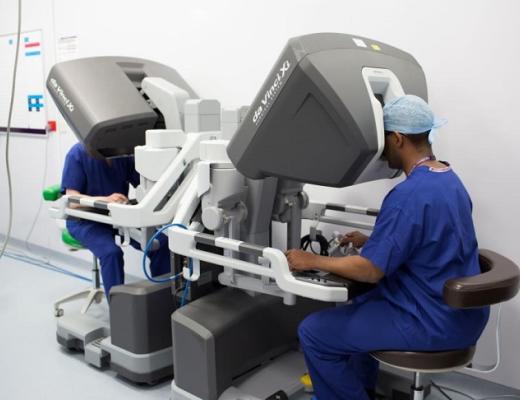 Two trainee surgeons sitting at two consoles, which is controlling a robot.