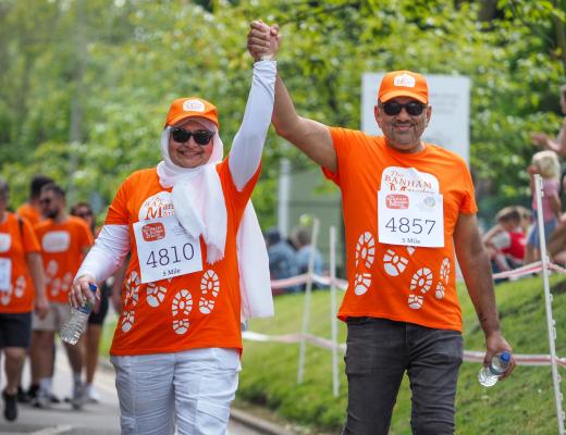 A couple smiling and holding their hands up as they approach the Banham Marsden March finish line in Sutton